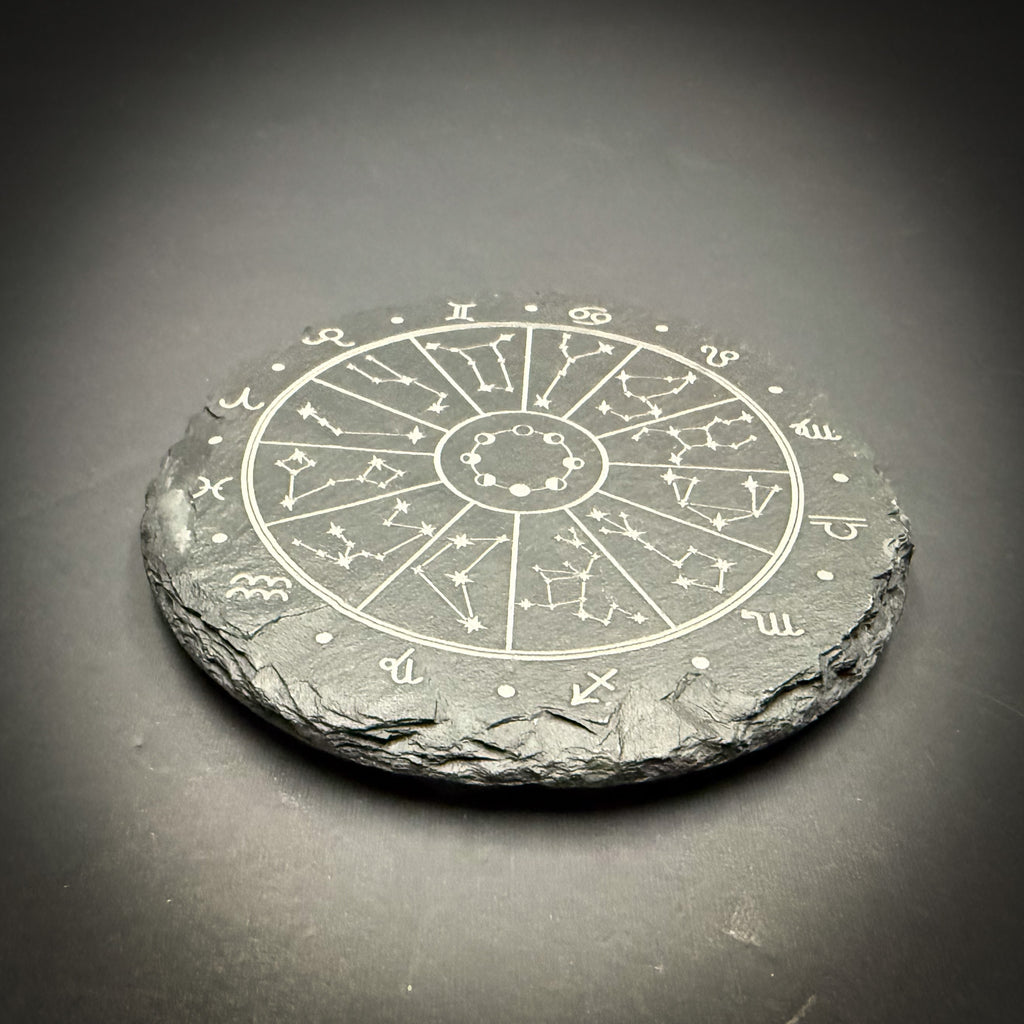A stone coaster with a zodiac wheel design on it.