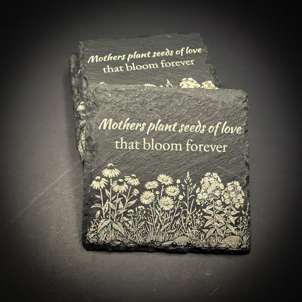 two slate coasters with a floral design and the text "Mothers plant seeds of love that bloom forever".