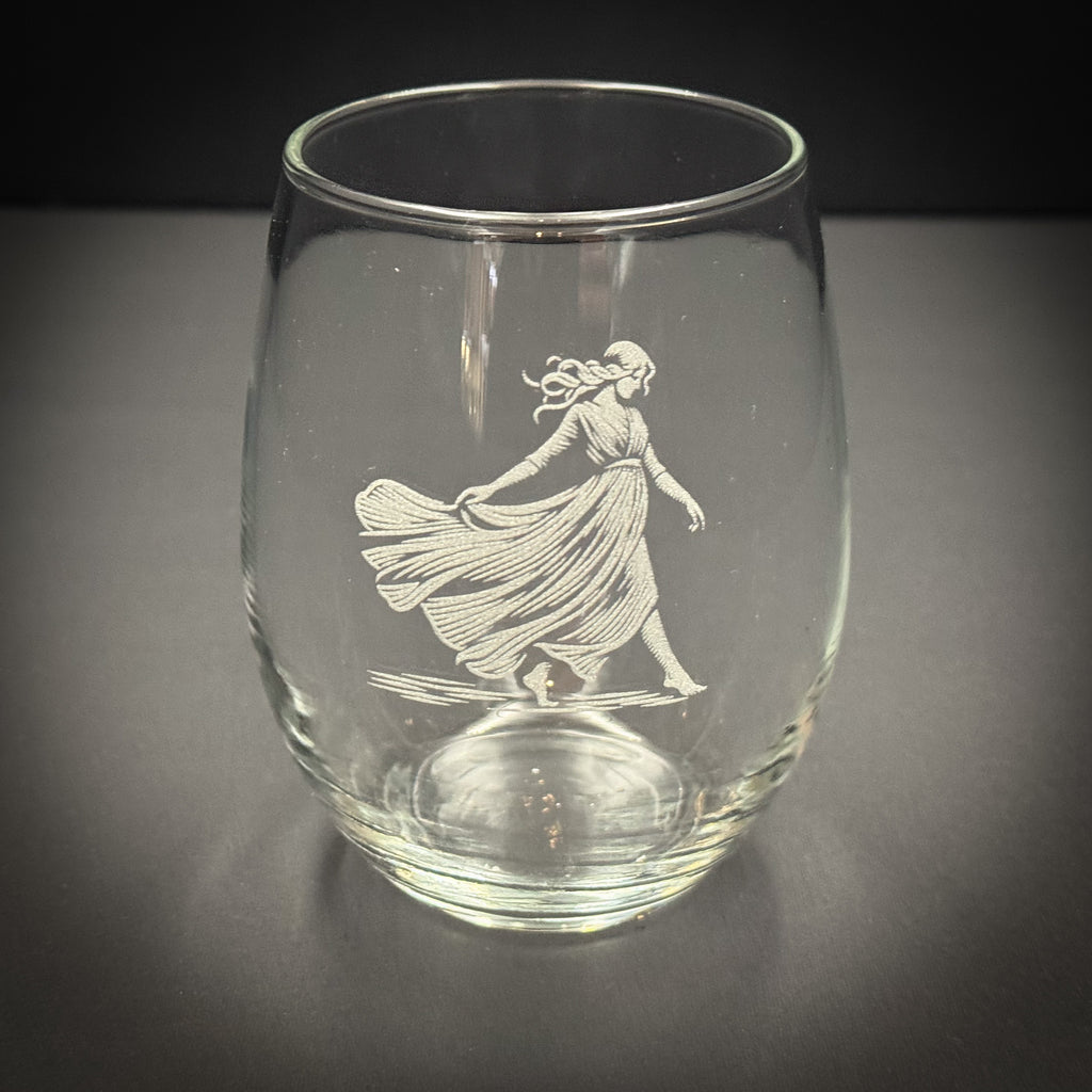 A glass with an etched image of a woman in a flowing dress on it.
