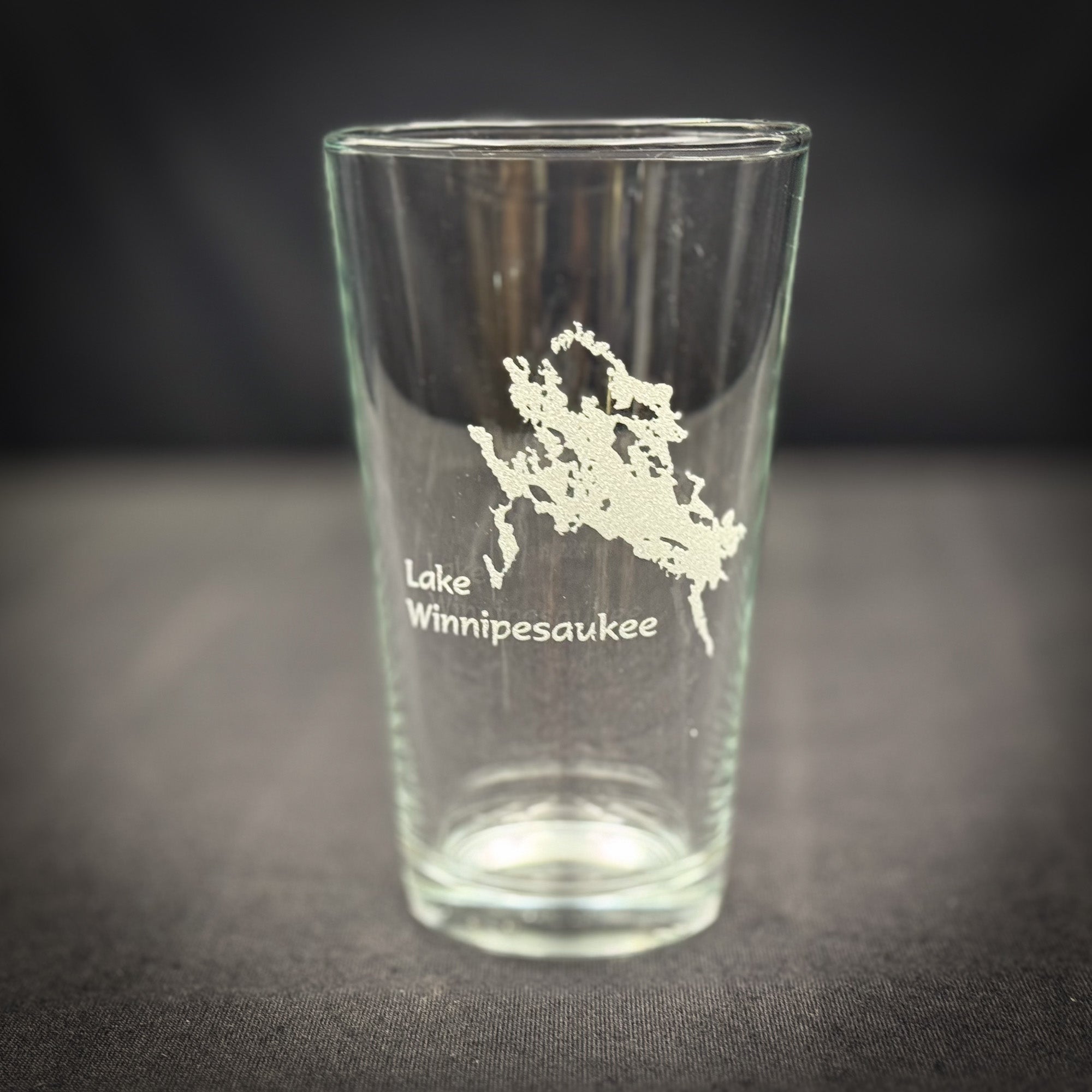 A clear glass with a white map of Lake Winnipesaukee printed on it.