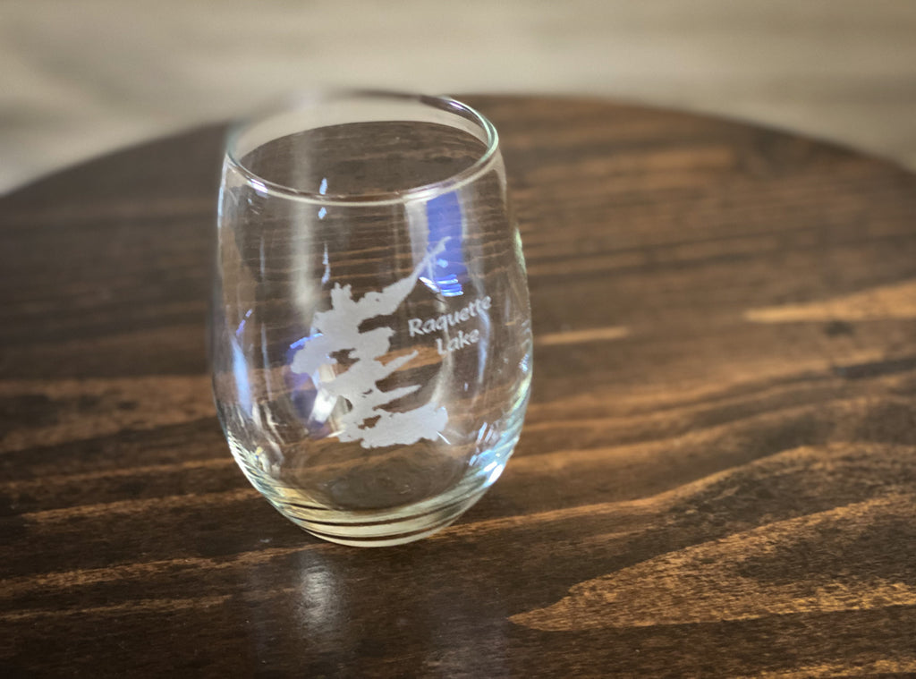 A clear glass with a white design on it, placed on a wooden surface.