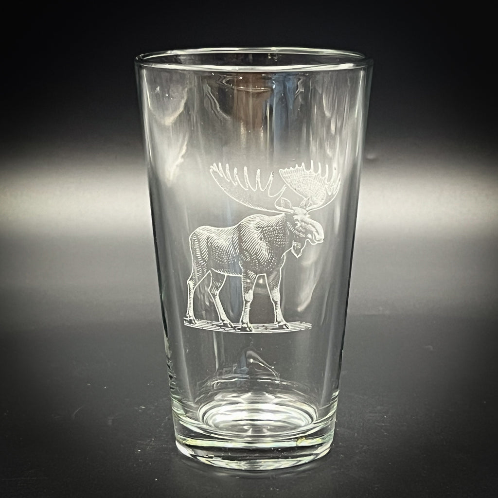 A clear glass with an etched image of a moose on it.