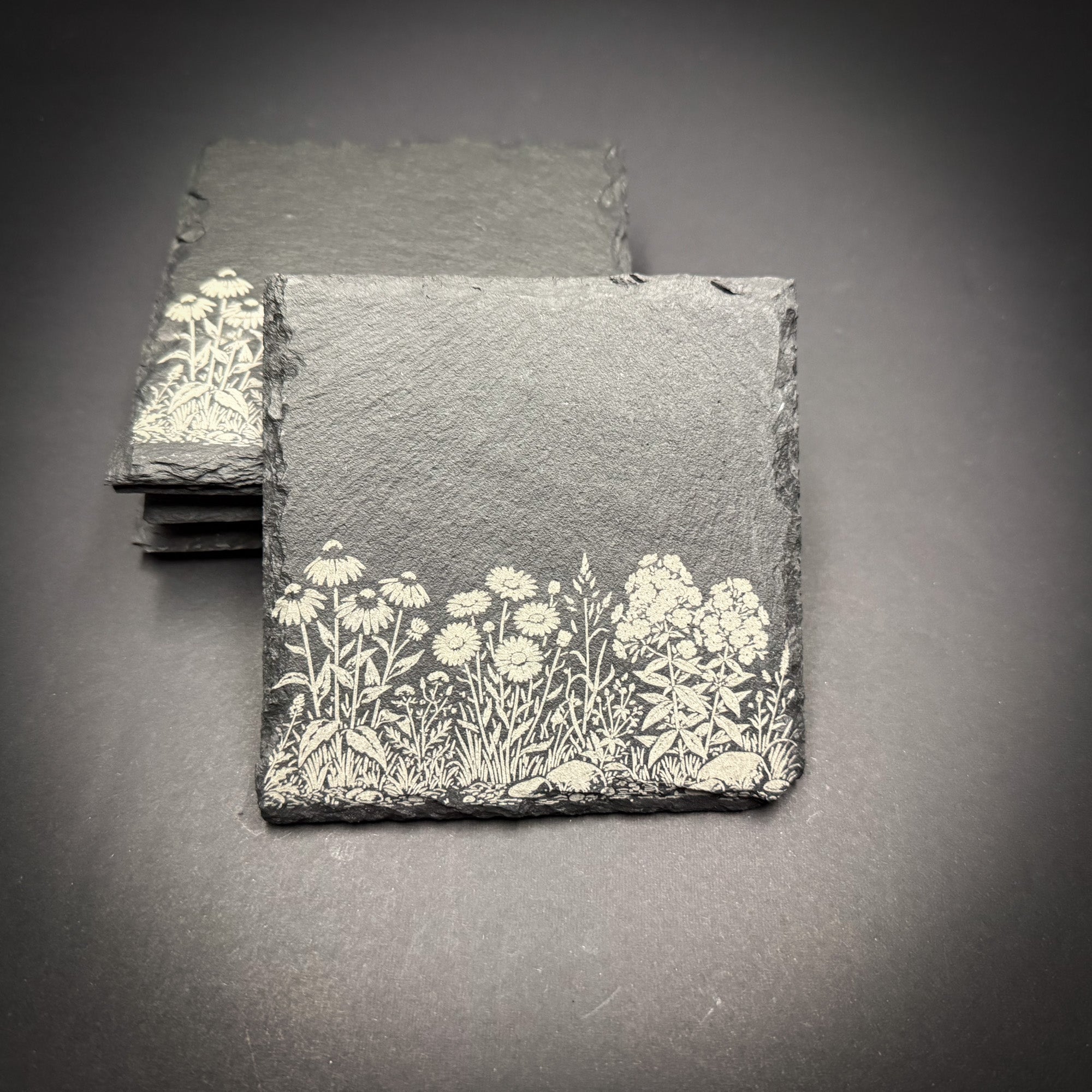 A close-up image of a slate coaster with a floral design on it.