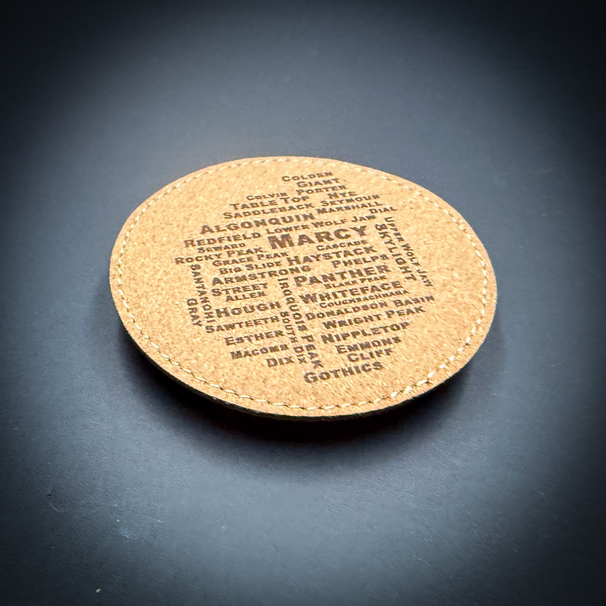 A cork coaster with the word "GOTHICS" printed on it, featuring a variety of words arranged in a circular pattern.