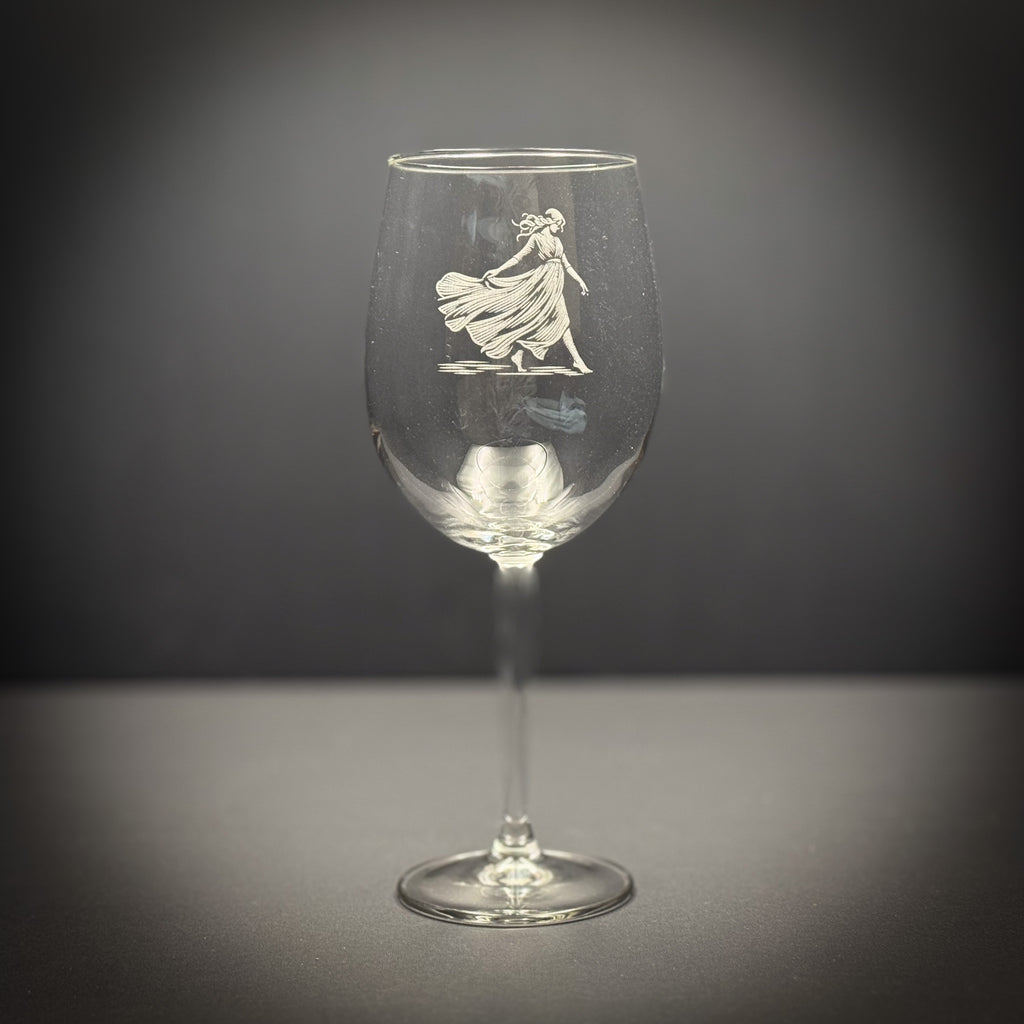 A wine glass with an etched image of a woman in a flowing dress on the stem.