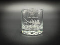 A clear glass with a design etched into it, featuring a stylized tree or plant pattern.