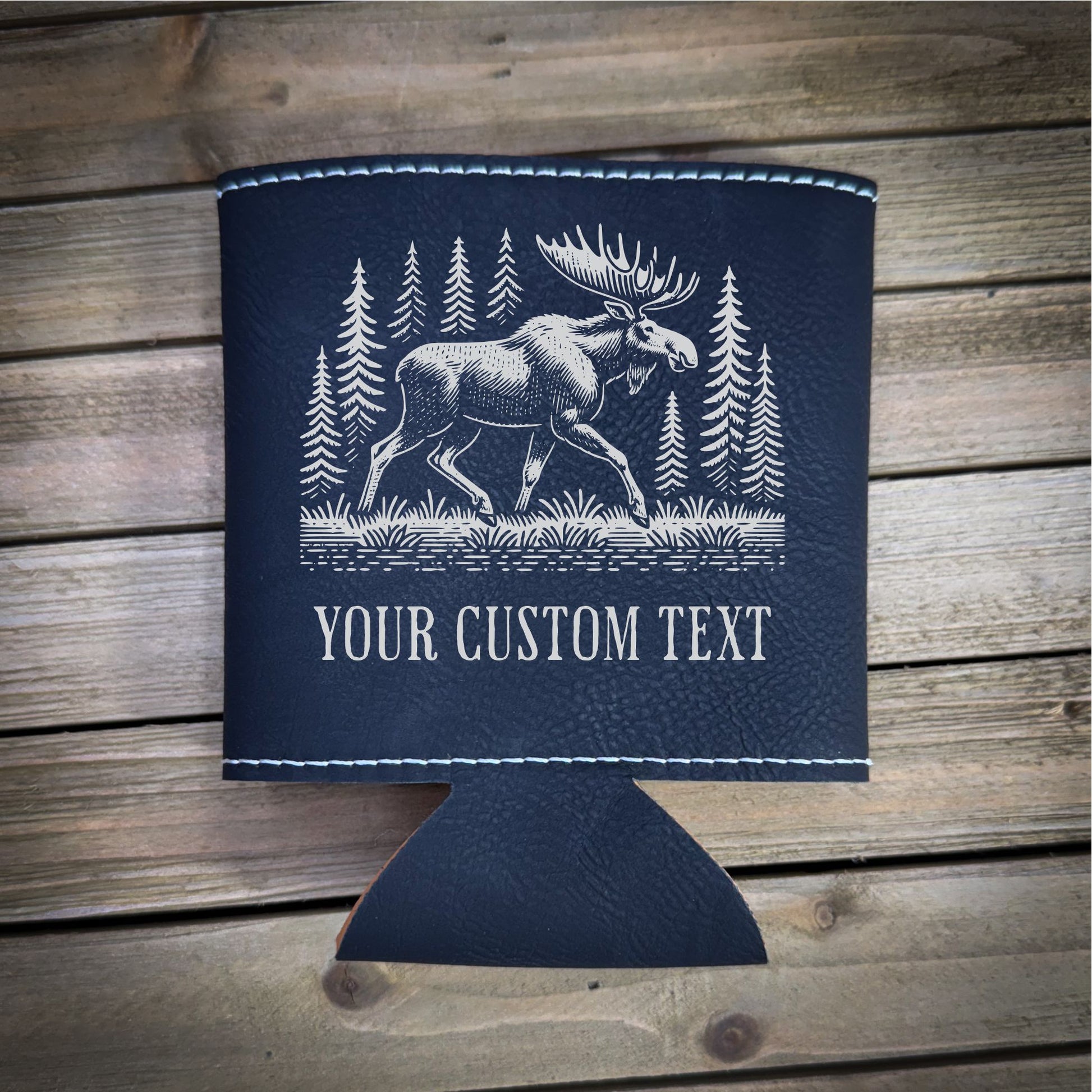 A black leather cooler with a white illustration of a moose and pine trees printed on it, along with the text "YOUR CUSTOM TEXT" printed below.