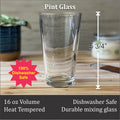 a pint glass on a wooden surface, with a plant in the background. The glass is described as a 16 oz volume, heat-tempered, and a durable mixing glass.