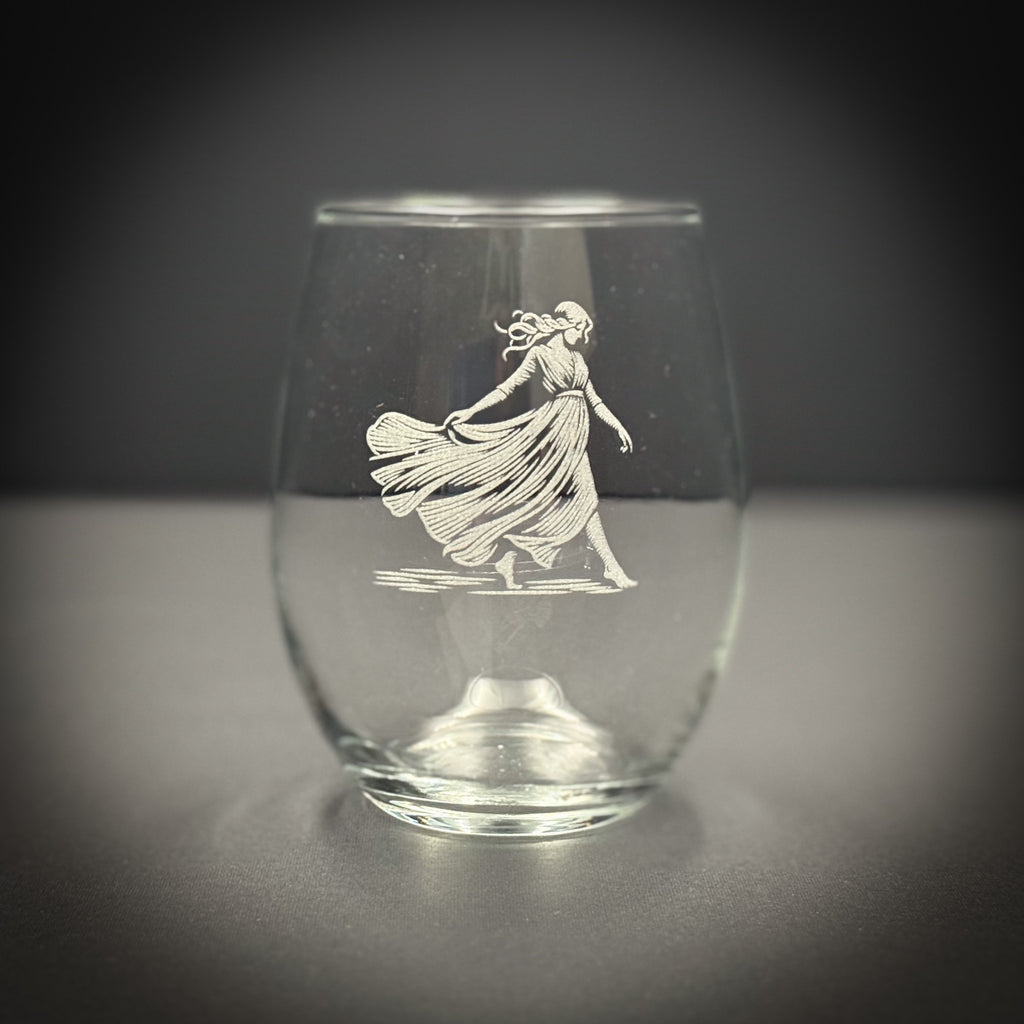 A glass with an etched image of a woman in a flowing dress on it.