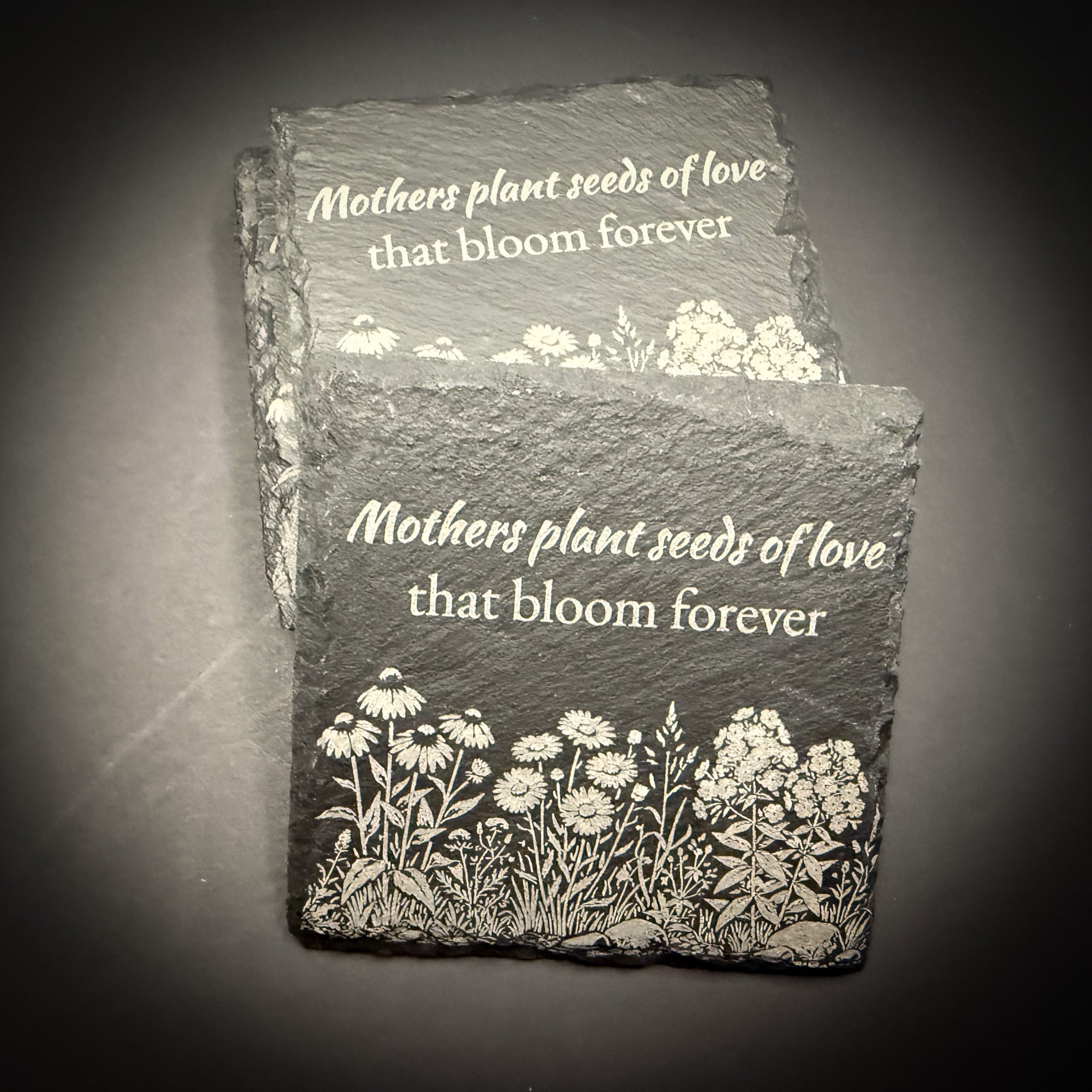 two slate coasters with a floral design and the text "Mothers plant seeds of love that bloom forever".