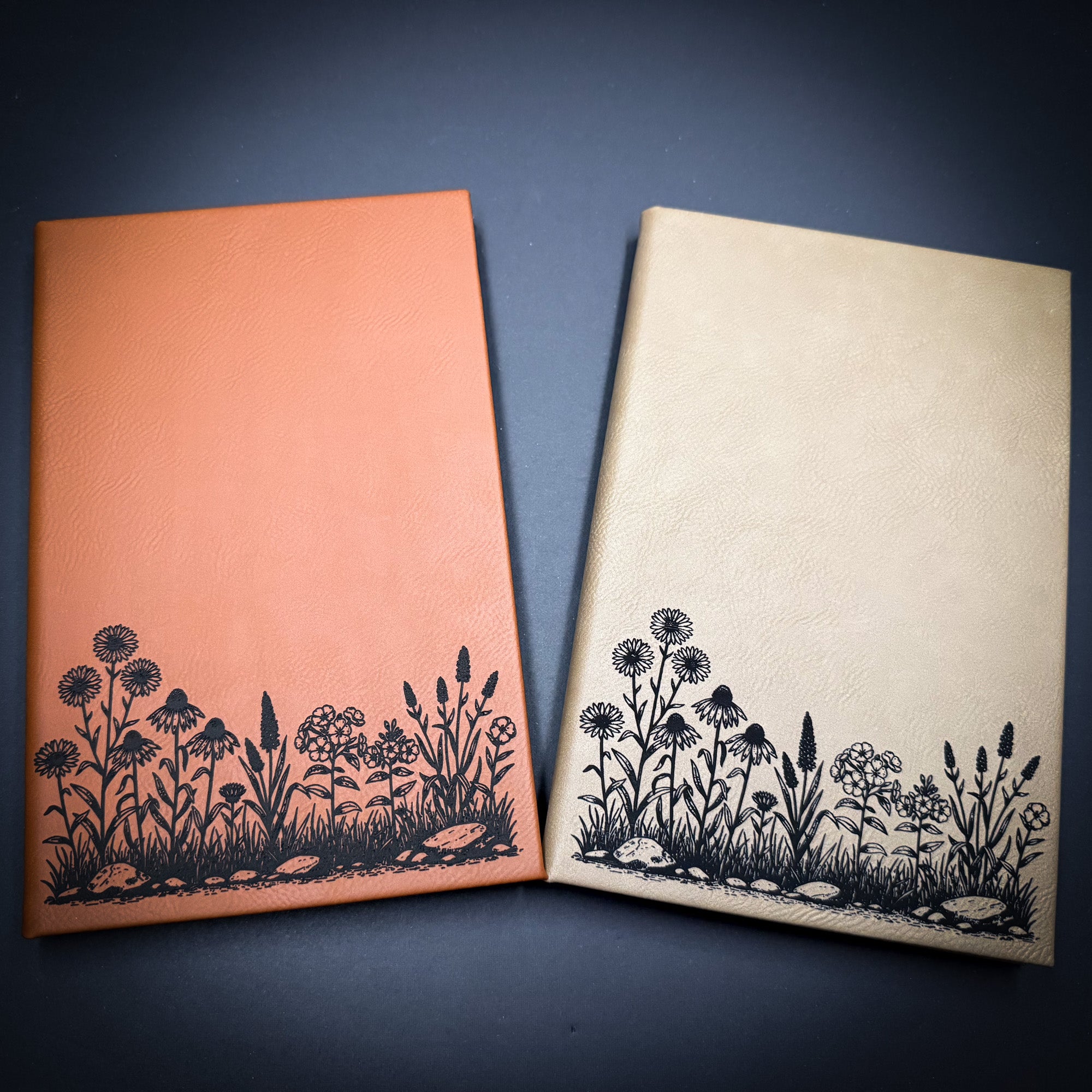 two notebooks with floral designs on the covers, placed side by side on a dark background.