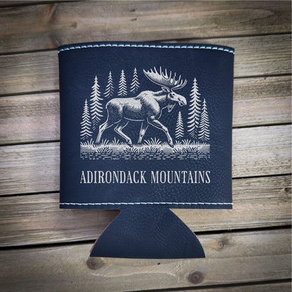 A black leather cooler with a white illustration of a moose and pine trees, along with the text "ADIRONDACK MOUNTAINS" printed on it.