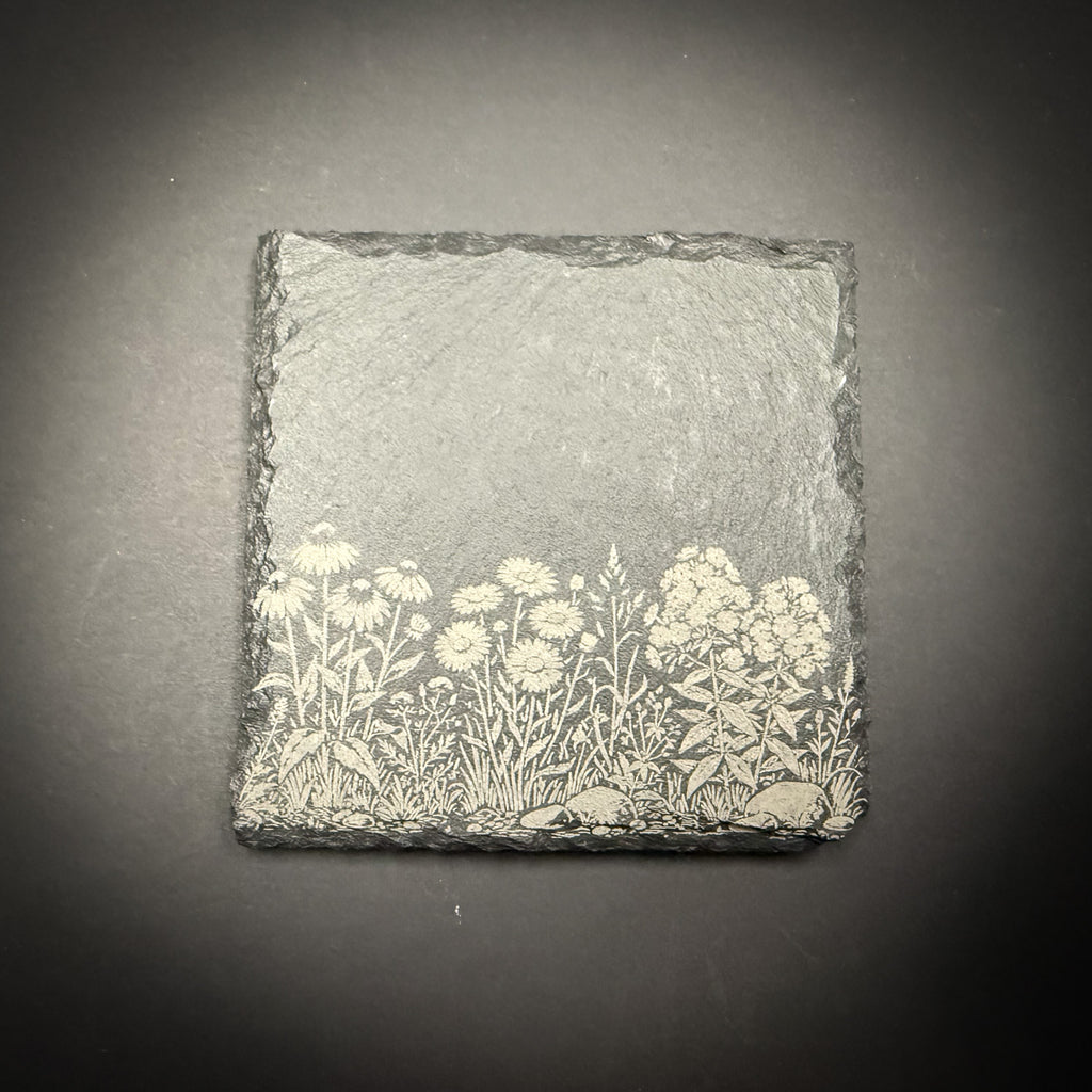 A square-shaped slate with a floral design on it, placed against a dark background.