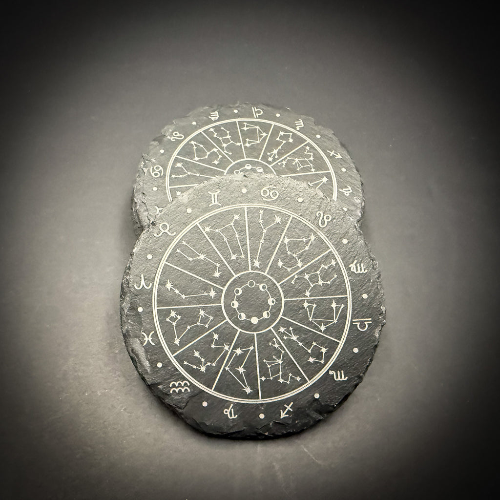 Two slate coasters with astrological charts and symbols printed on them.