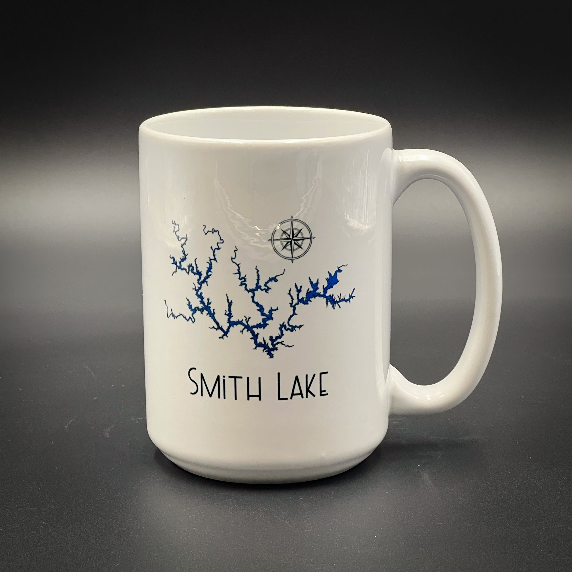 A white ceramic mug with a blue design depicting a river or lake, along with the text "SMITH LAKE" printed on it.